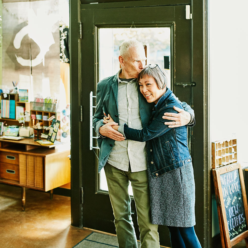 Una pareja se abraza en la entrada de una tienda de ropa local.