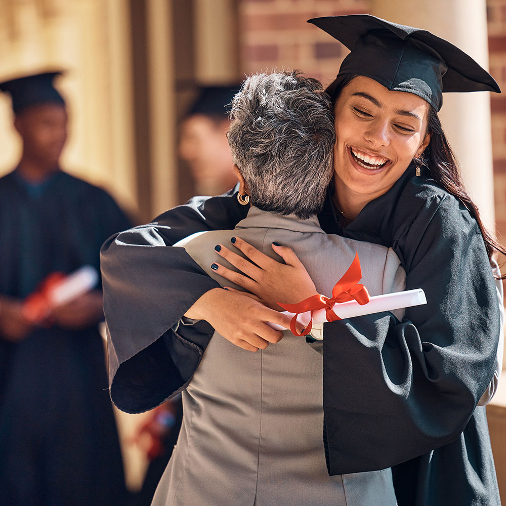 Una mujer abraza a otra mujer mayor en una ceremonia de graduación