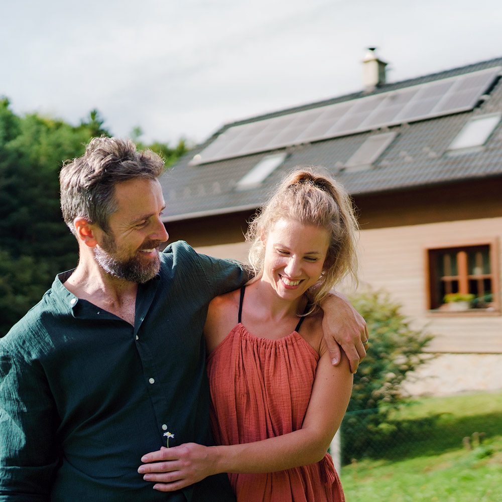 Pareja cerca de una casa con paneles solares