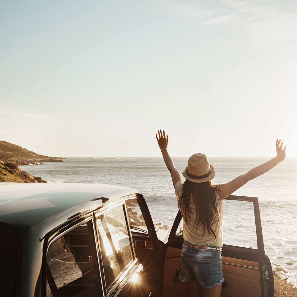Una mujer del lado del pasajero de un auto que recibe el sol