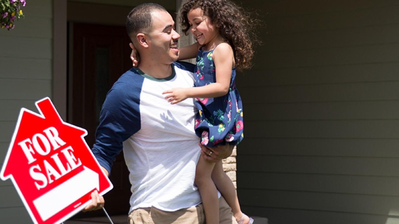 Hombre con su hija sosteniendo un cartel de casa en venta