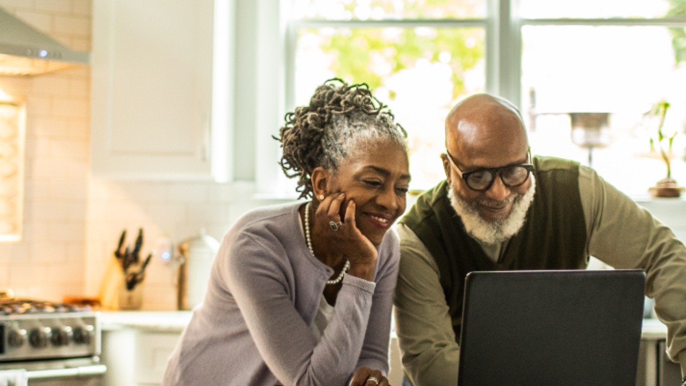 pareja de adultos mayores mirando una computadora portátil y sonriendo