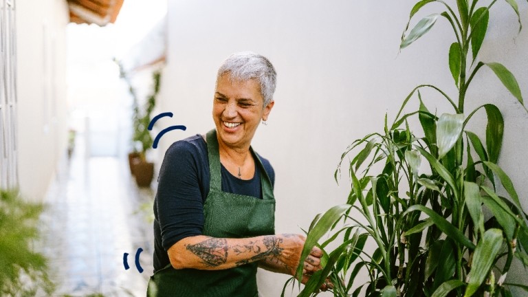 Mujer parada junto a unas plantas. 