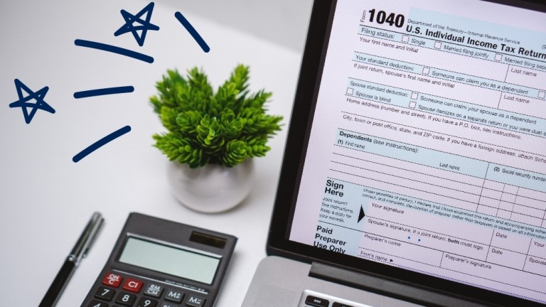 Plant on a desk next to a computer with a 1040 tax form displayed