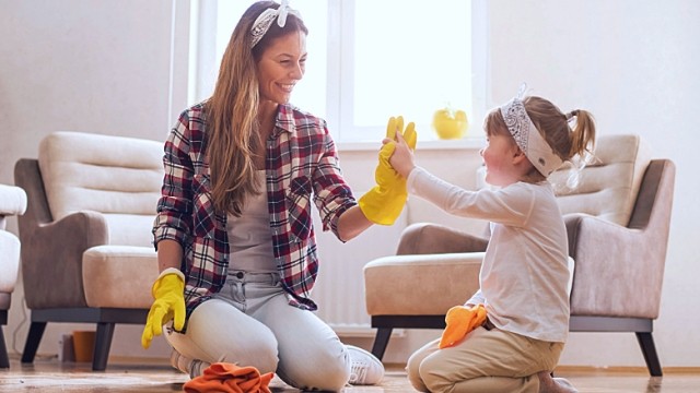 Woman and girl with cleaning gloves on are cleaning the floor