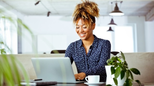 Woman with ponytail working on laptop in an office with plants