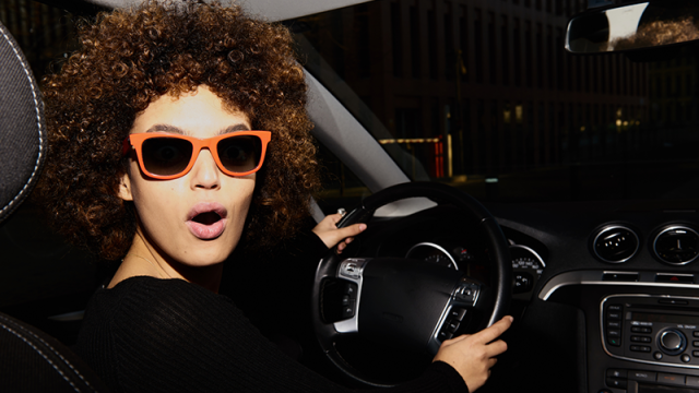 Young woman in new car with orange sunglasses