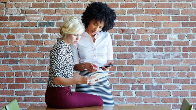 Two young women around a conference table