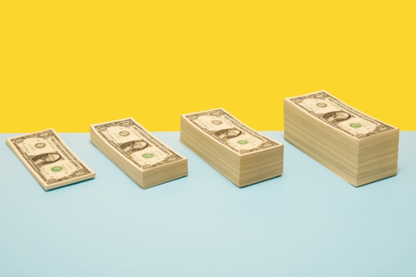 Four increasing stacks of dollar bills lined up in a row.