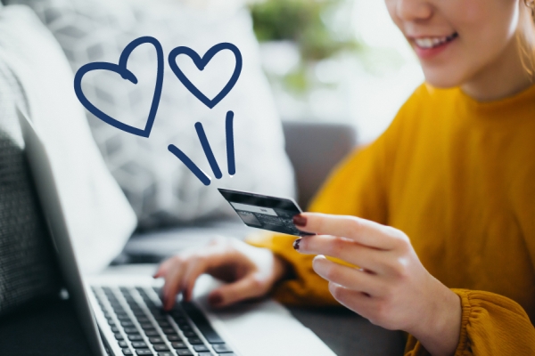 Woman holding a credit card with squiggle hearts in the air around her. 
