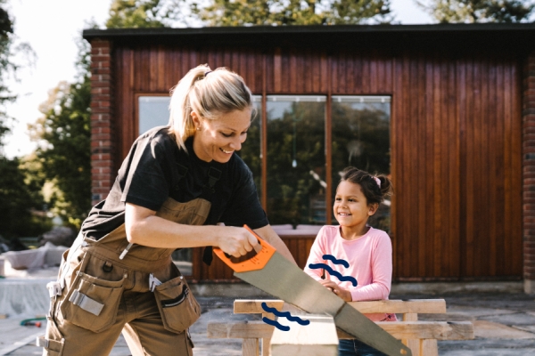 Woman using a saw to cup a piece of wood. 
