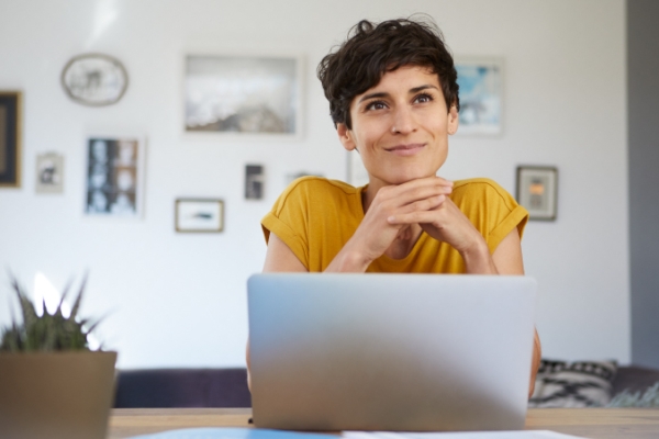 A content, short-haired person at home working on their laptop.