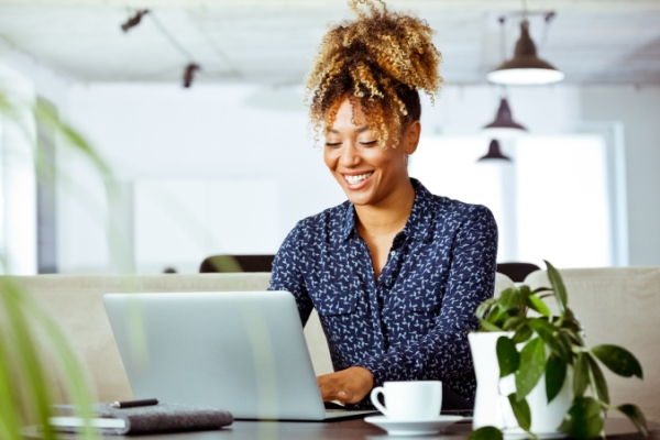 Woman with ponytail working on laptop in an office with plants