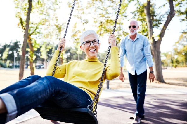 Una pareja de adultos mayores en un columpio del parque