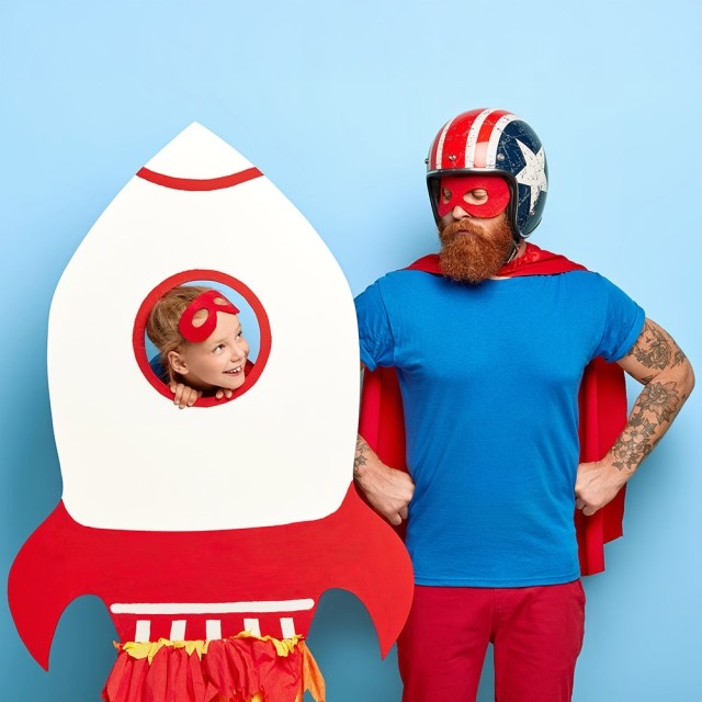 Un padre y su hija que juegan a ser cohete y superhéroe